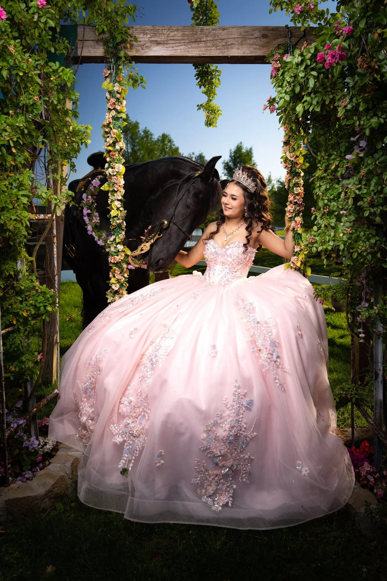 Quinceañera in a pink gown posing in the grass at a ranch
