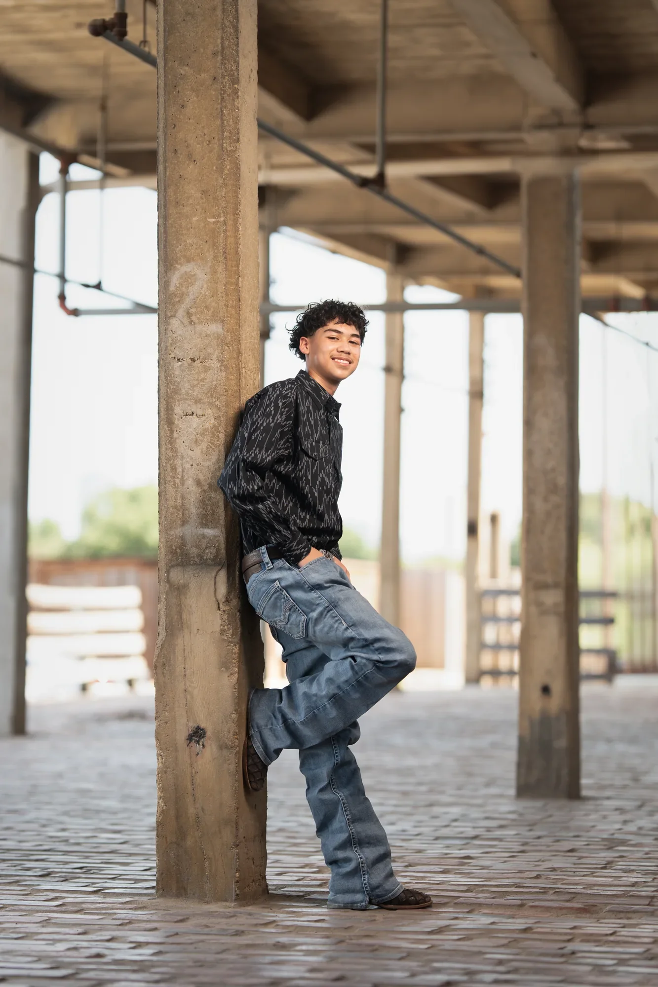 Retrato de sesión previa de un quinceañero con camisa vaquera en una locación industrial de DFW