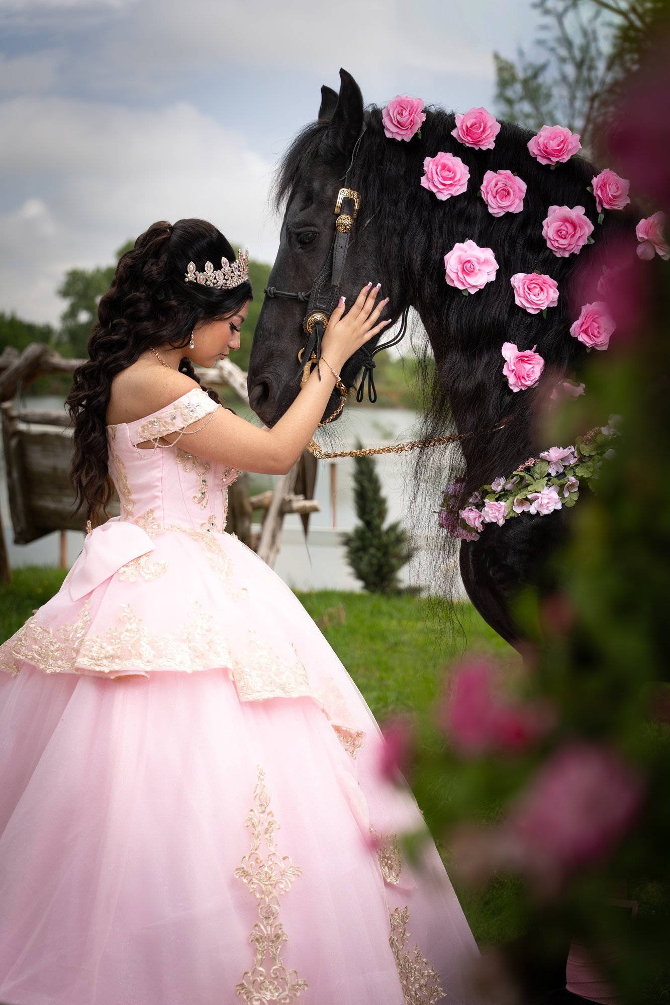 Quinceañera resting her hand on a horse decorated with pink roses