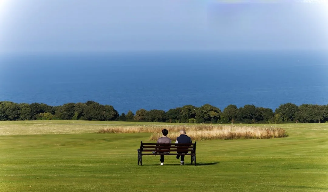 people sitting on a bench in a meadow