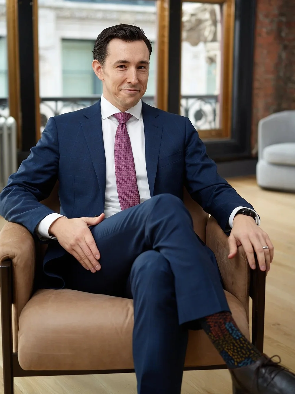 Seated finance executive portrait in a navy suit, photographed in a modern New York office