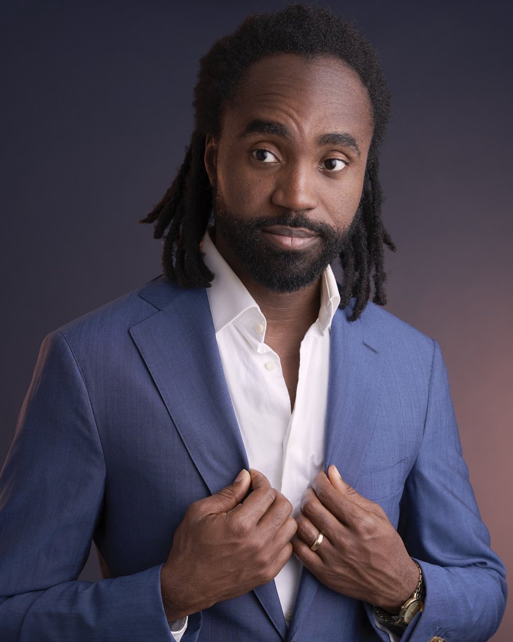 Creative studio portrait of a man in a blue suit looking to the side against a dark gradient background