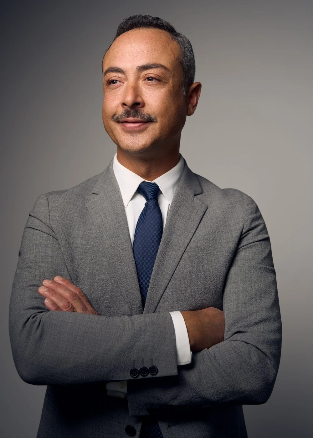 Executive headshot of a man in a gray suit looking off camera against a neutral studio background