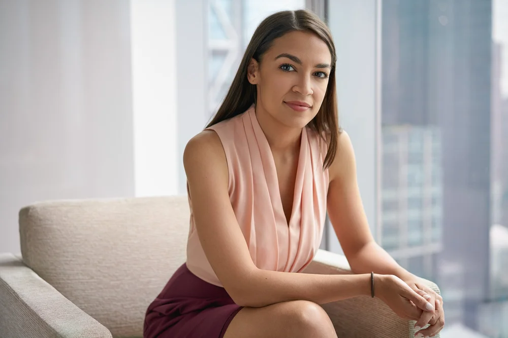 Alexandria Ocasio-Cortez seated beside a window for an editorial portrait commissioned by The New Yorker