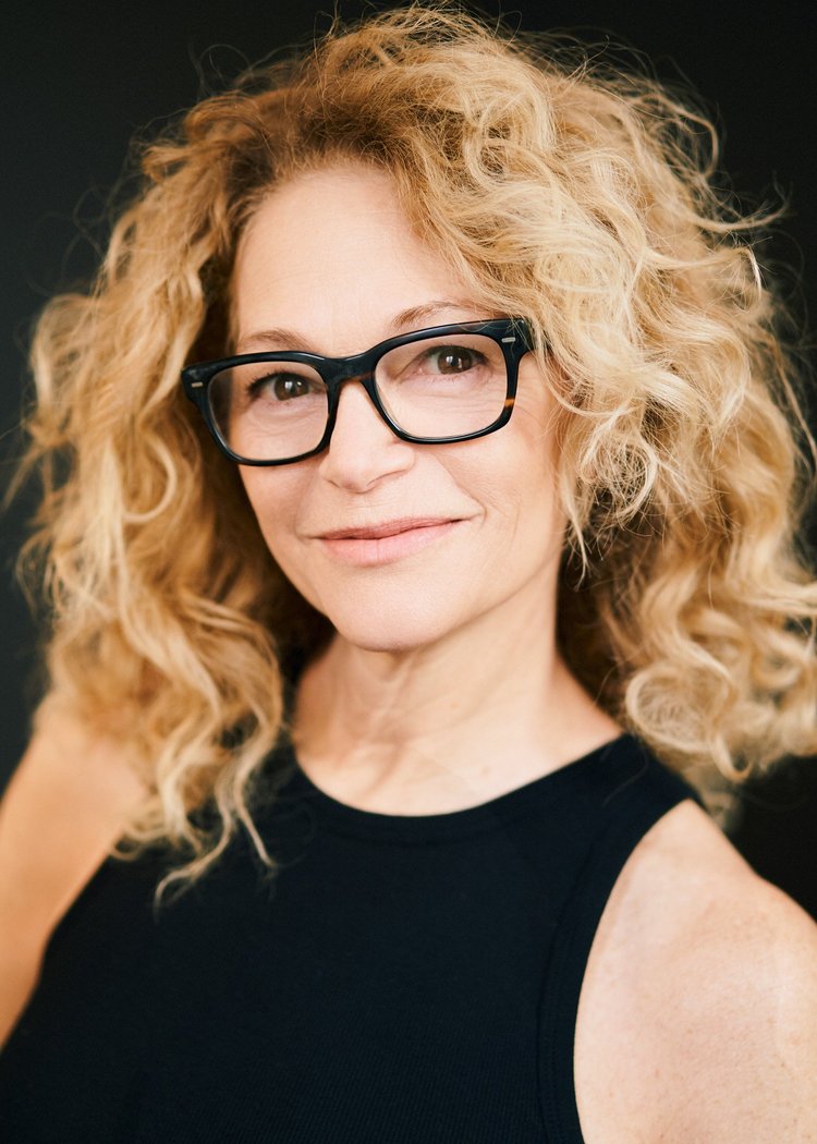 Actor headshot of a woman with blonde curly hair in a black sleeveless top, NYC