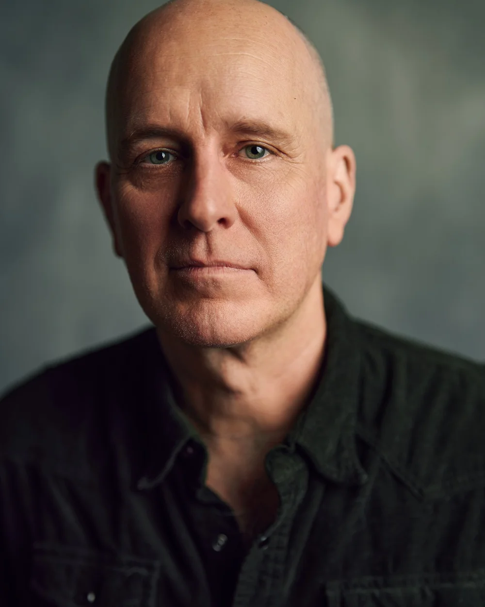 Close actor headshot of Kelly Aucoin against a softly textured gray studio background