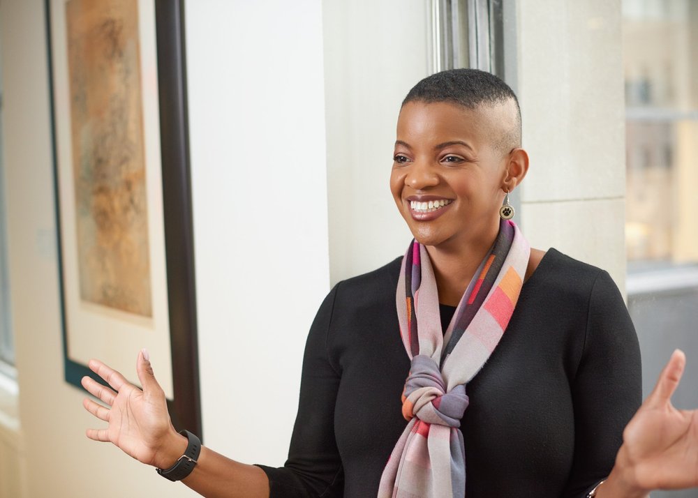 Corporate branding photograph of a woman smiling and gesturing during a conversation in an office