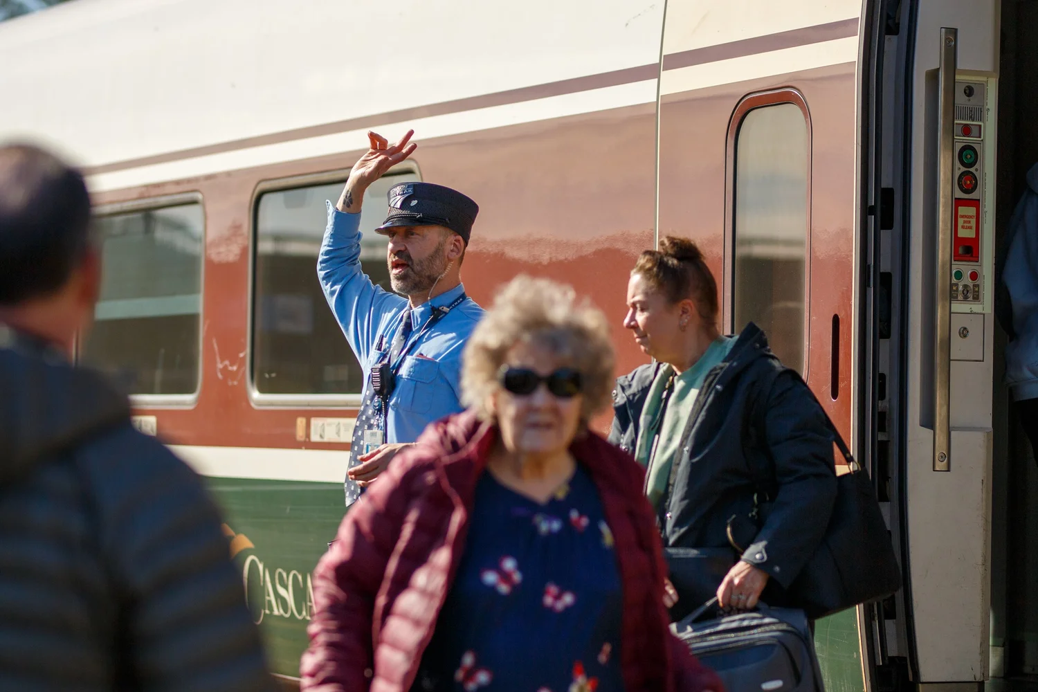 Amtrak Cascades conductor leaning out of the train door to greet passengers on the platform in Olympia