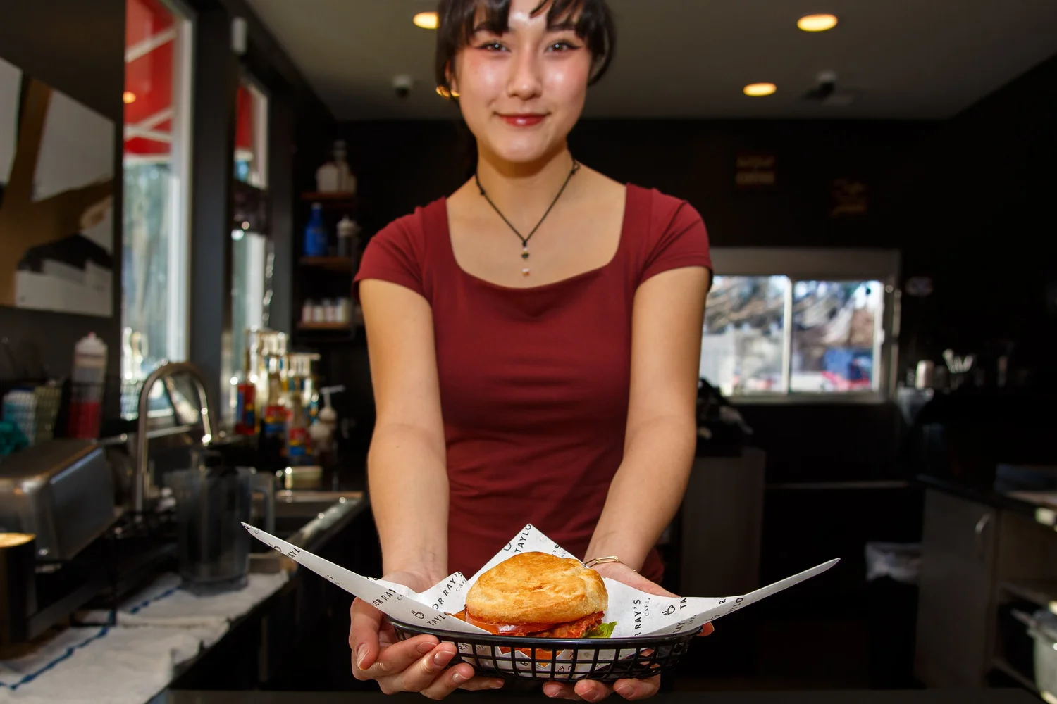 Barista handing a customer a plated BLT sandwich across the counter at Taylor Ray's Cafe in Olympia