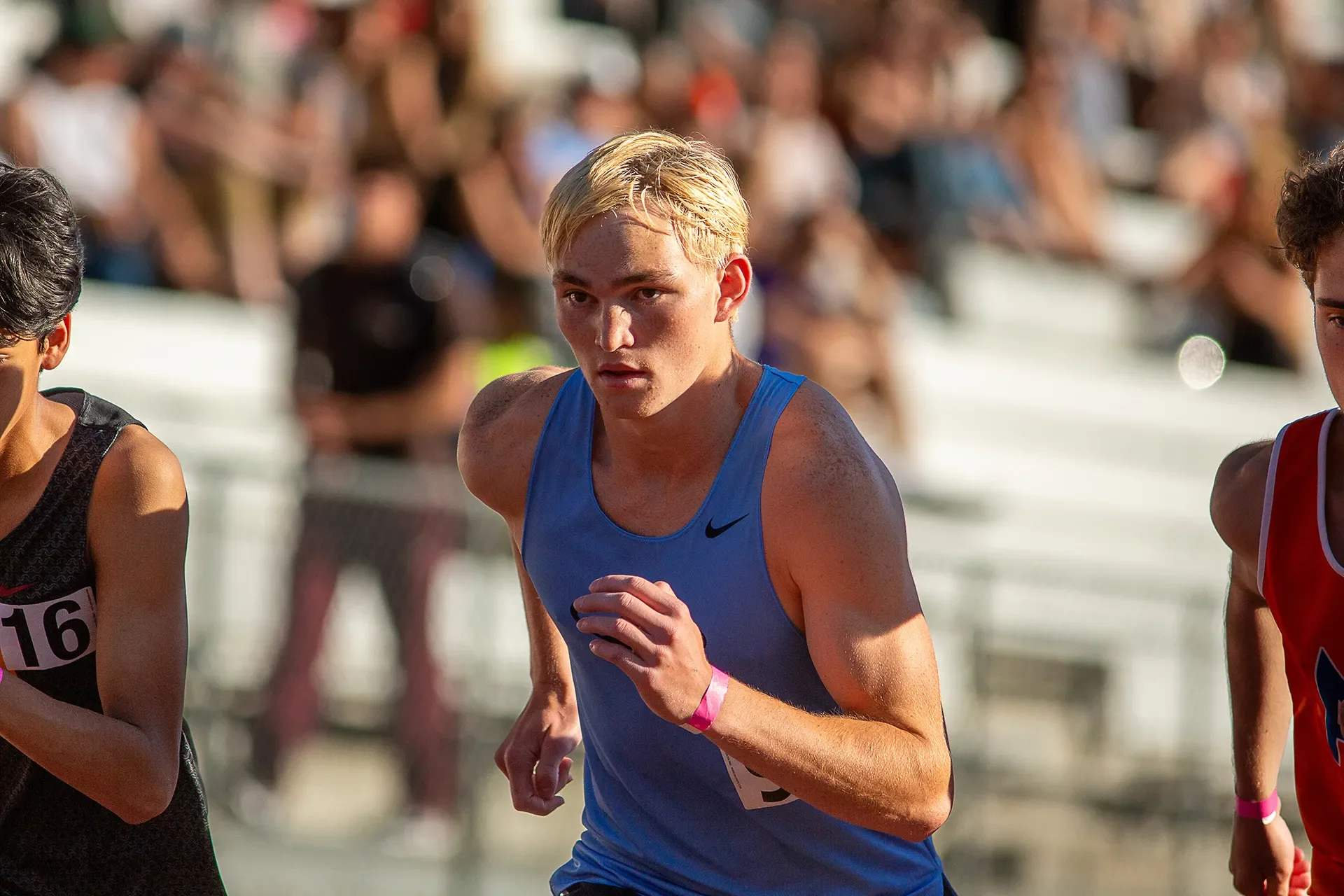 Max Dower racing on the track, bib number 16, stadium crowd in background