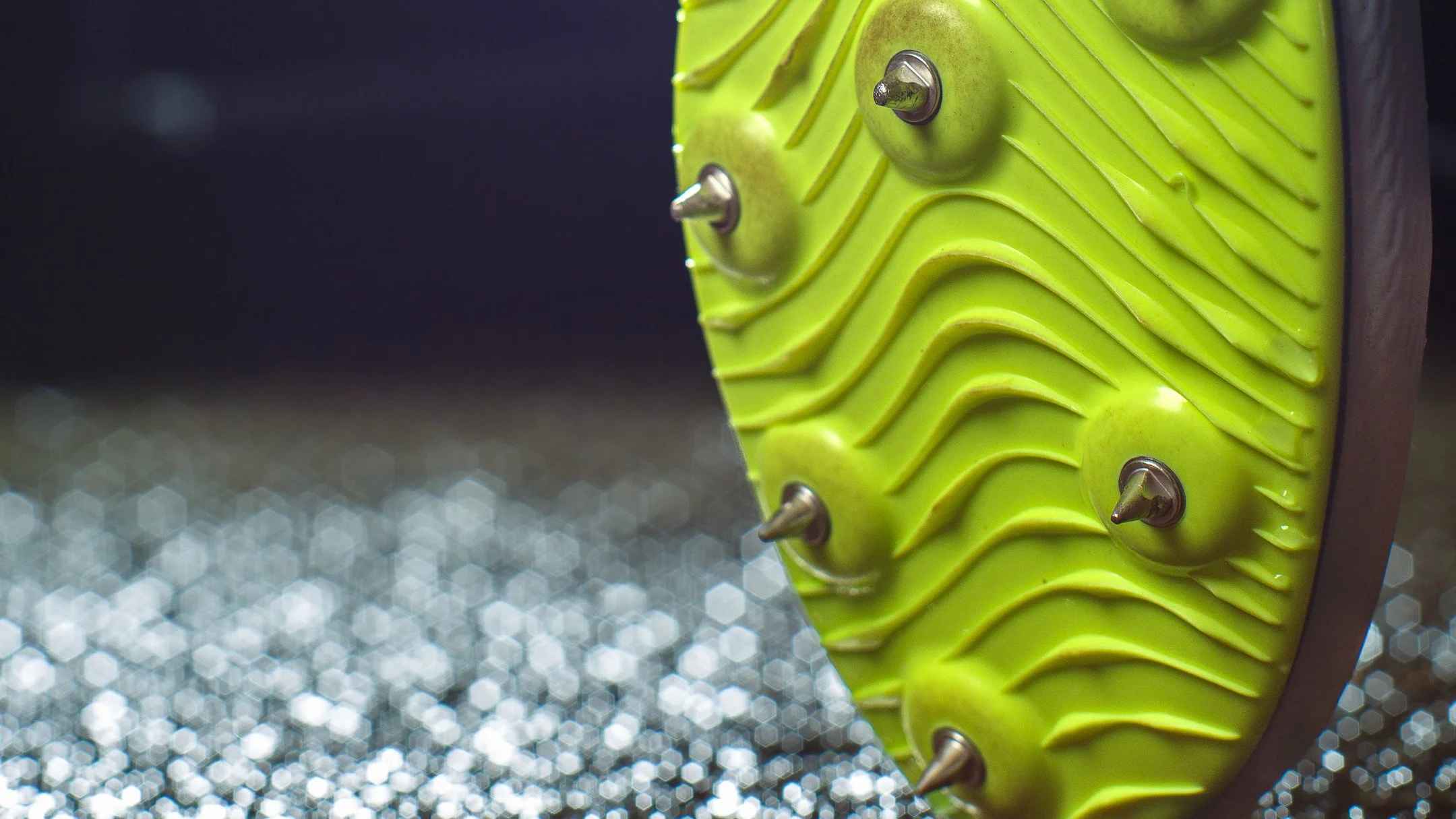 Close-up of a bright neon cross country spike on gravel — pre-race texture and detail