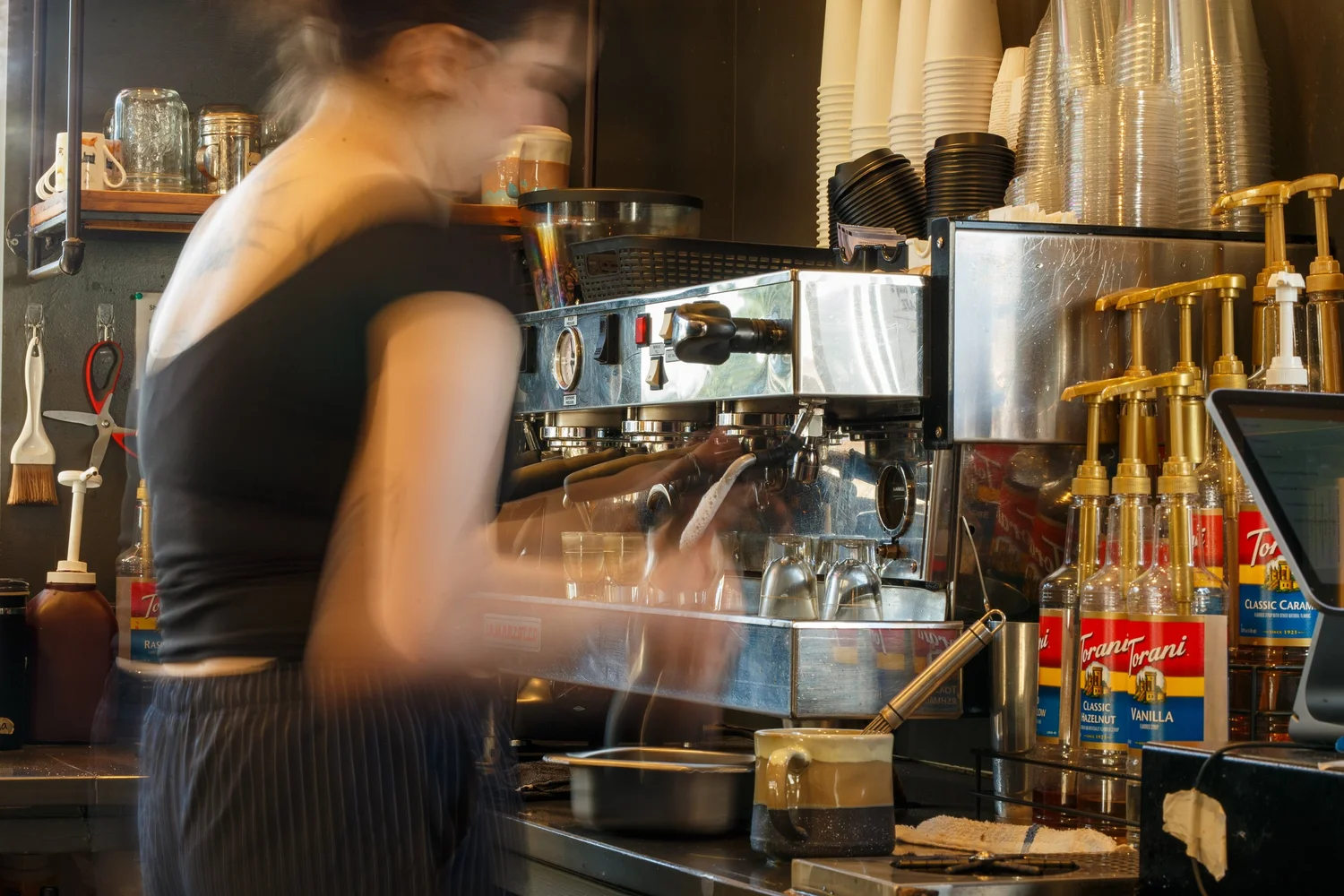 Barista pouring a latte, captured with motion blur, at Taylor Ray's Cafe in Olympia