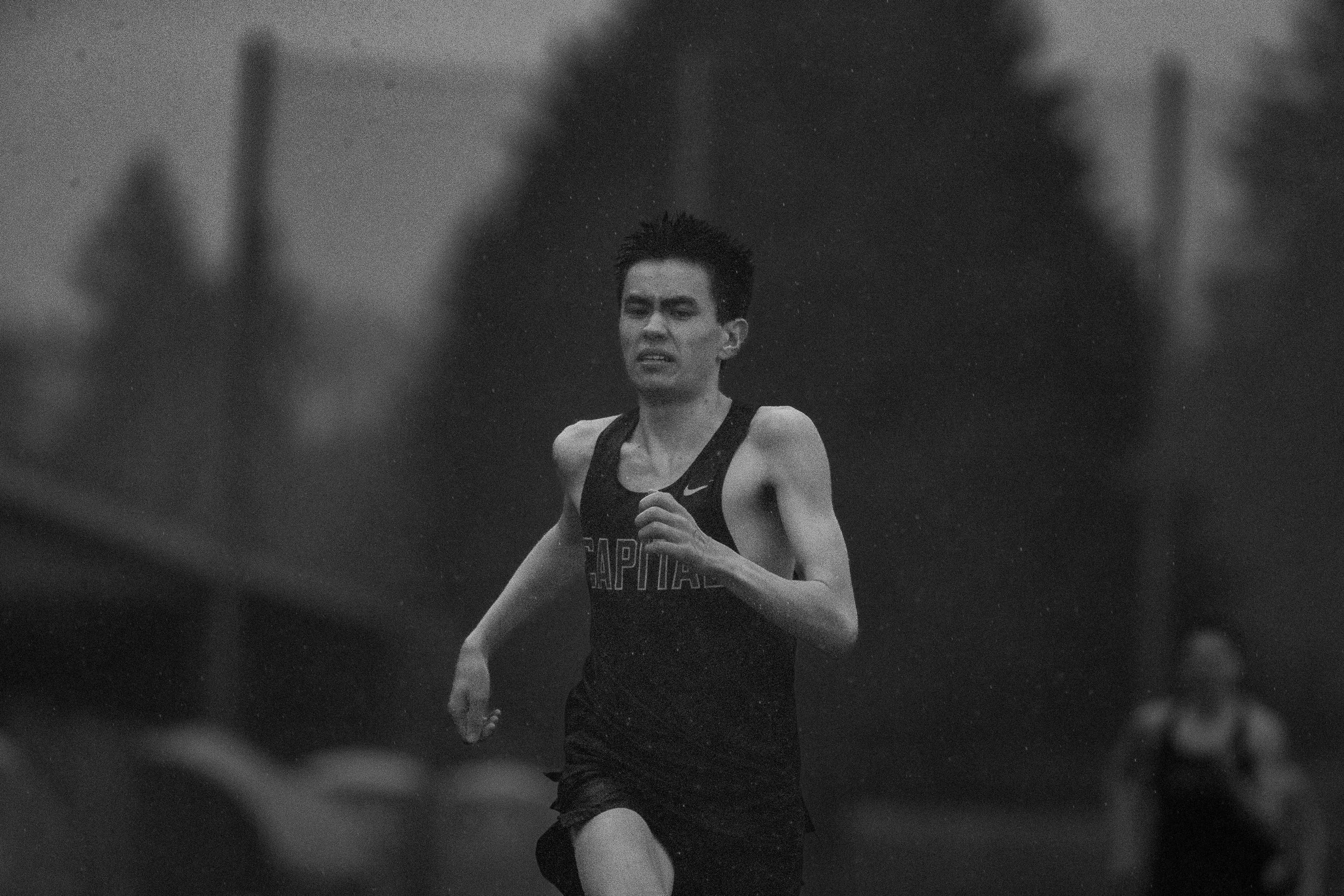 Track and field athlete caught mid-action in the driving rain.