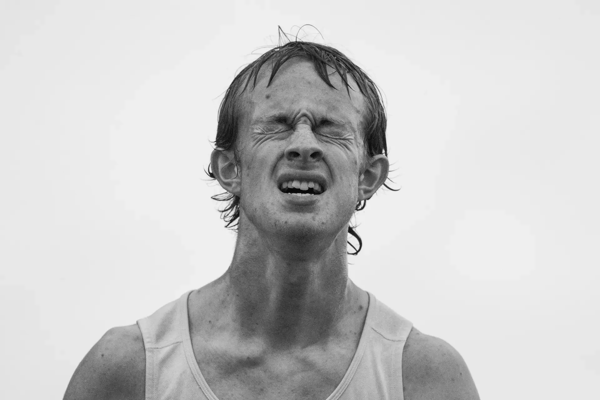 High-contrast portrait of an Olympia High School track athlete showing extreme physical exertion.
