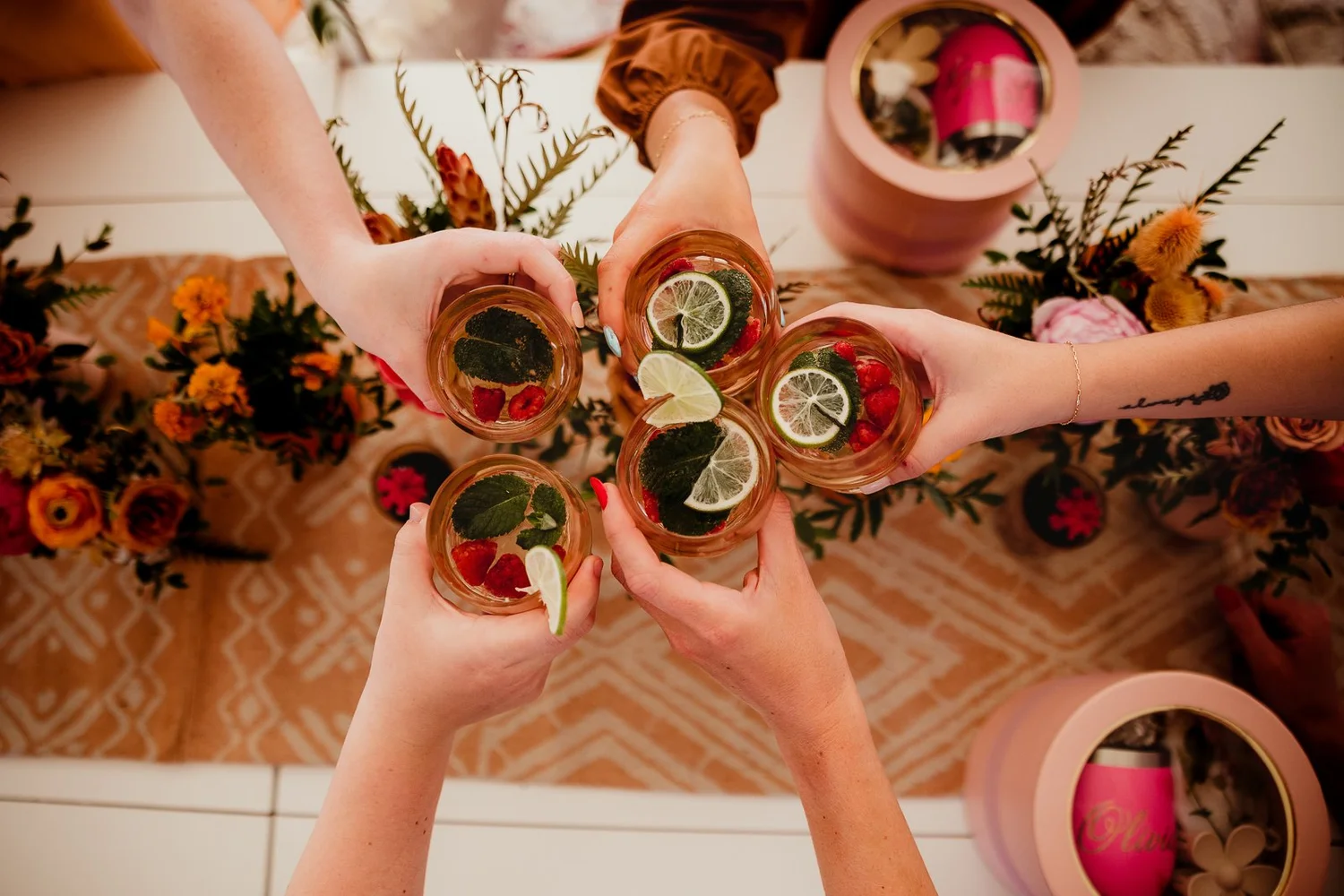 Glasses garnished with citrus, berries and mint raised in a toast. Photograph by Dave Stremikis.