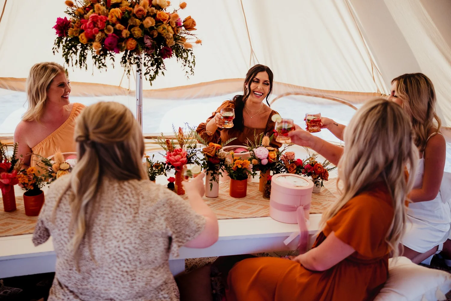 Friends sharing a toast around a flower-filled table, photographed by Dave Stremikis.