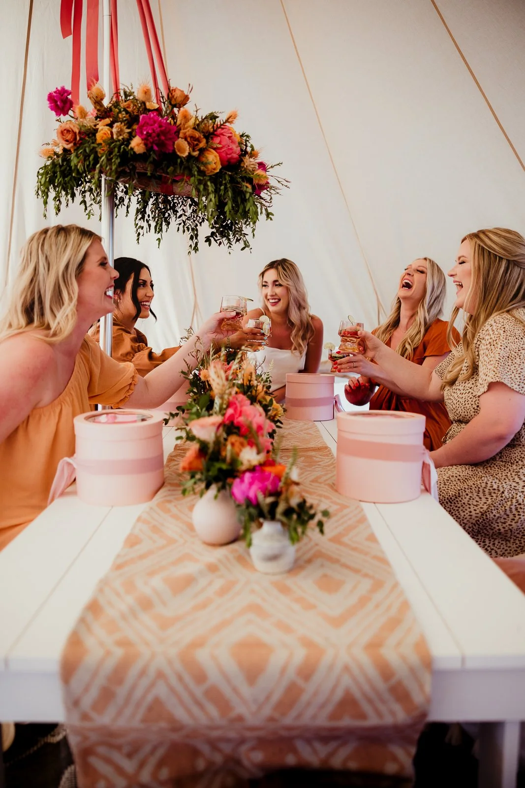 Friends raising glasses around a flower-filled table. Dave Stremikis Photography, Copper Feather / WedPlan editorial.