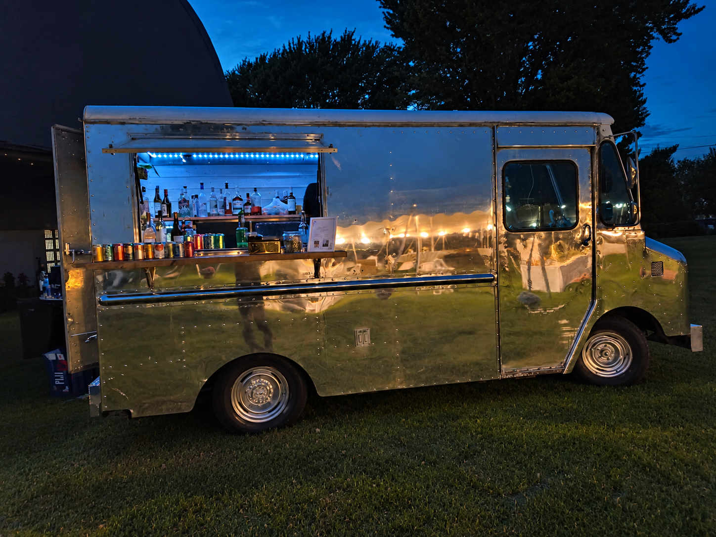 Lavender Haze Mobile’s silver truck set up for bar service at dusk, with warm light reflected on its polished body.