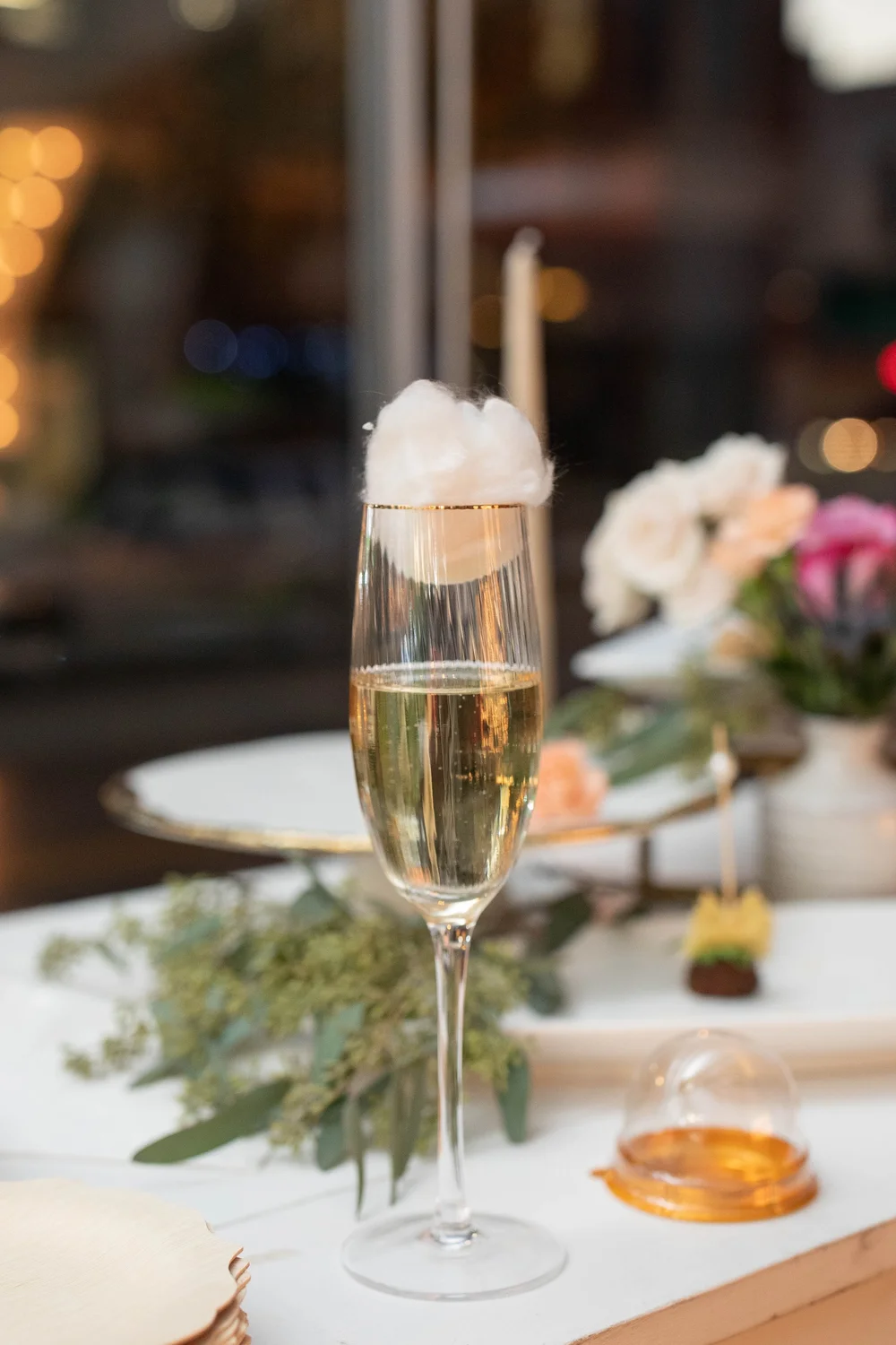 A delicate sparkling drink beside flowers and candlelight. Photograph by Kuffel Photography.
