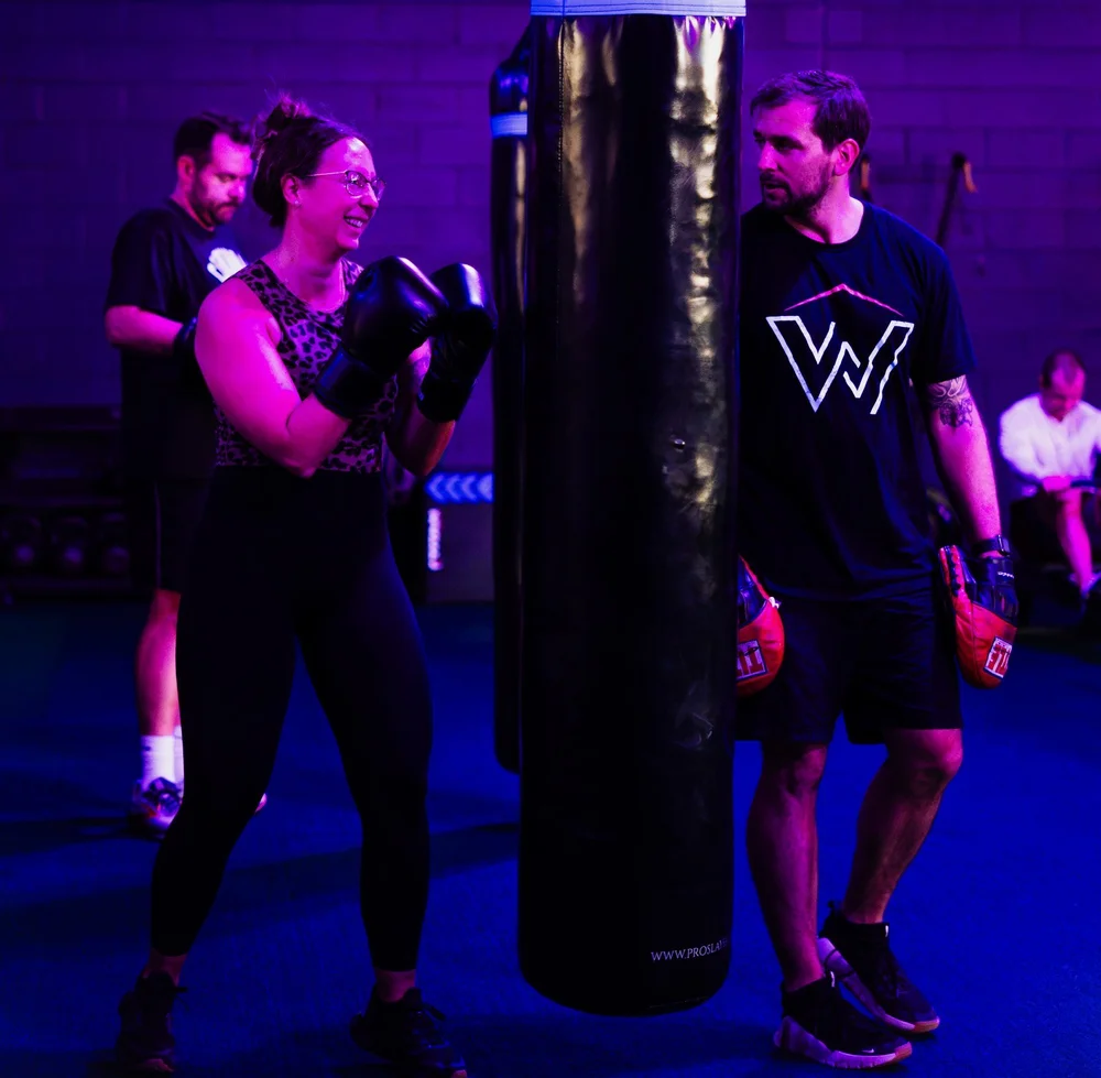 Coach Mike holding pads for a member at the bag