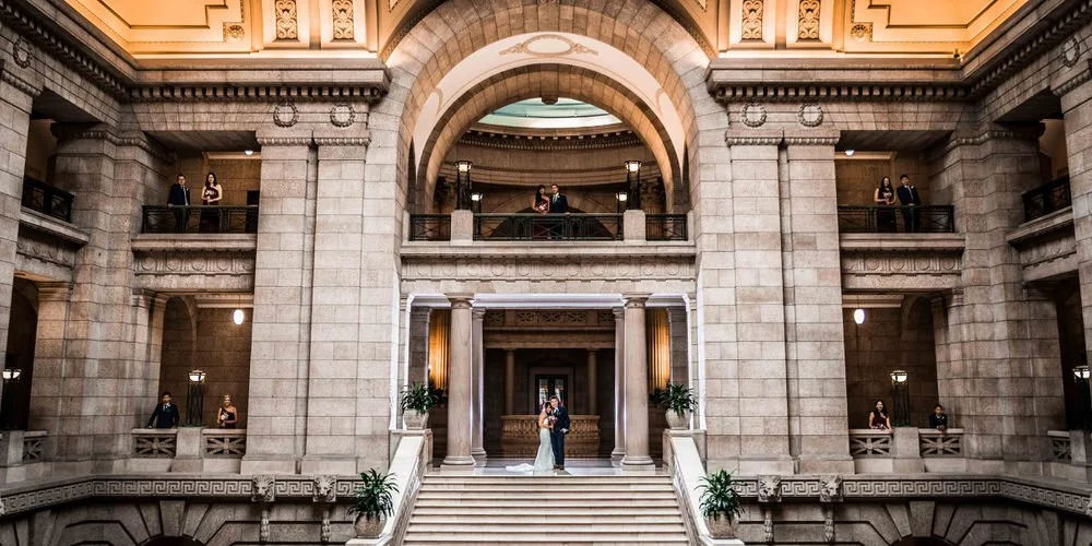 Wedding party portrait — full group posed in front of an old stone building