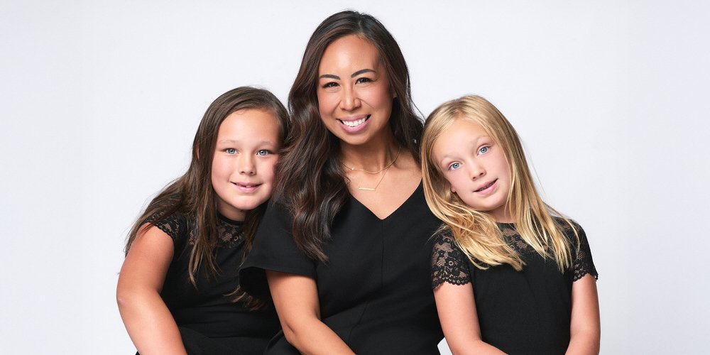 Studio family portrait — mom seated with two daughters in matching black outfits