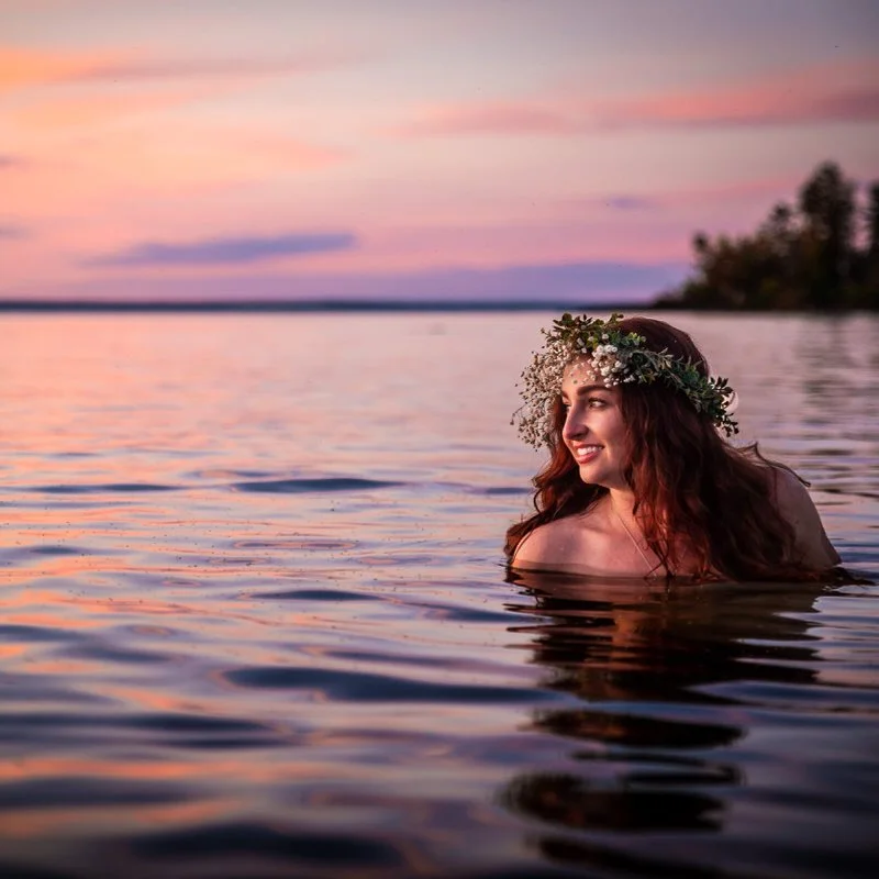 Outdoor bridal portrait — bride standing in a lake at sunset