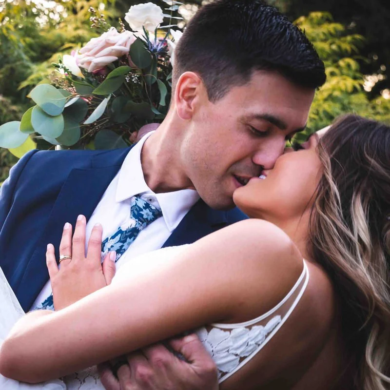 Outdoor wedding portrait — couple sharing a romantic kiss in a garden