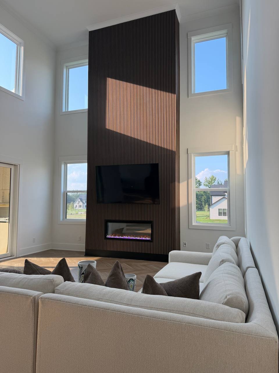 Floor-to-ceiling wood slat media wall with fireplace, 20-foot ceiling, Charlotte NC
