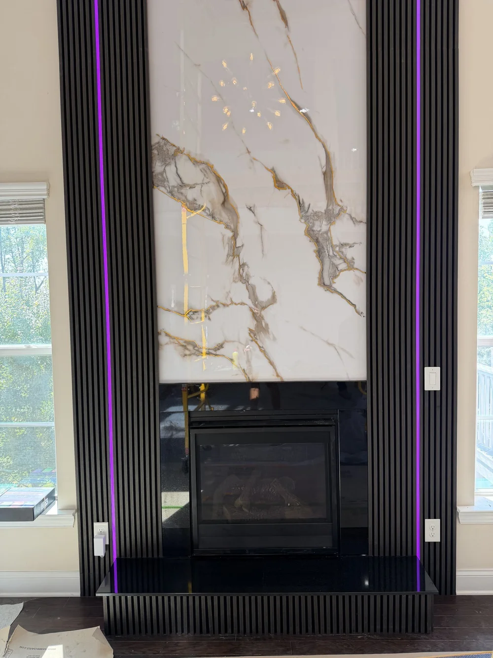 Two-story marble-look fireplace wall with dark slats and LED lighting, Charlotte NC