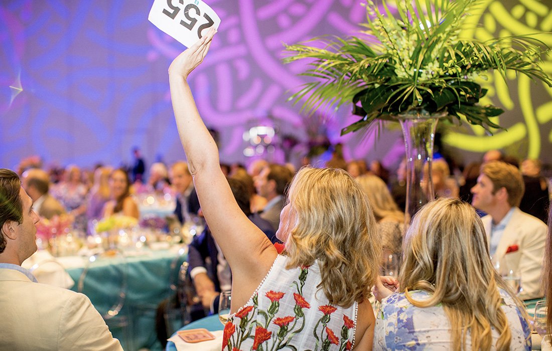 Parent bidding at festive fundraising auction dinner gala.