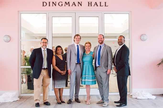 Six stakeholders at ribbon cutting event posing in front of Dingman .