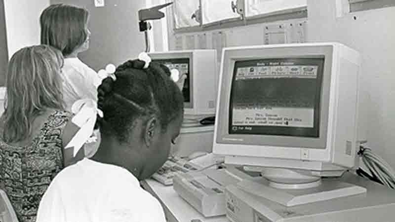 Blck and white photo of students working at vintage computers.