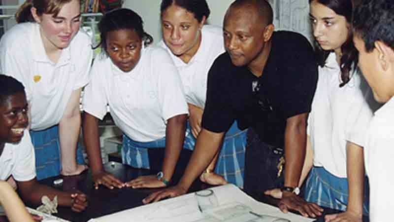 Students and teacher gathered around a table looking at project.