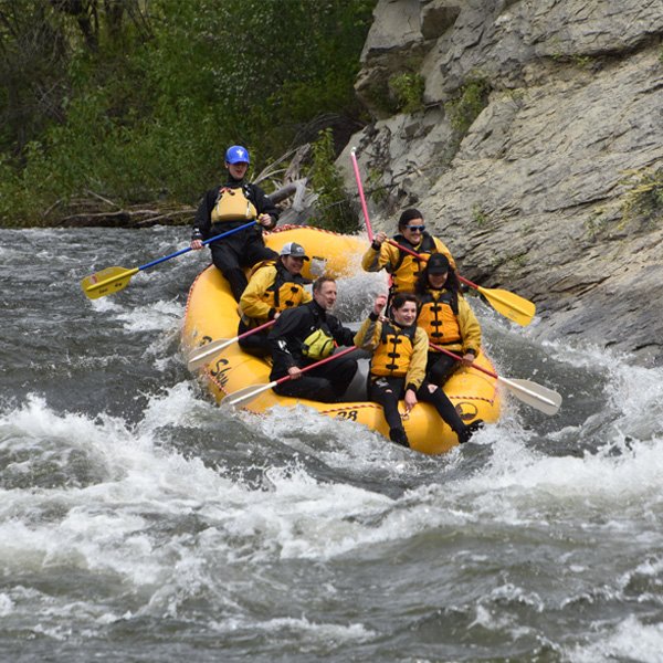 A group of people going through a rapid in a raft.