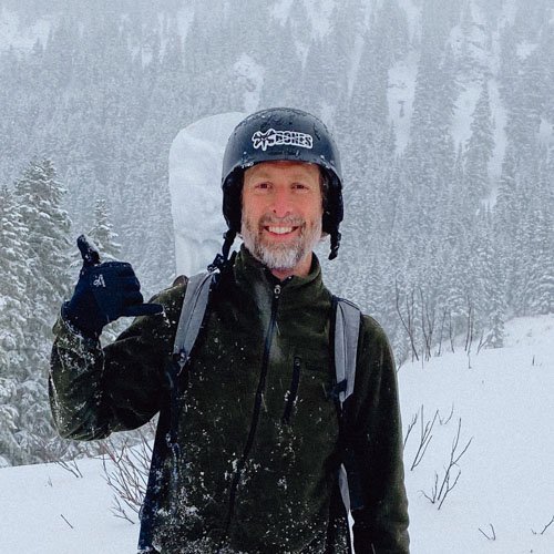 Rhett Stephens holding up a shaka hand gesture and smiling in the snow.