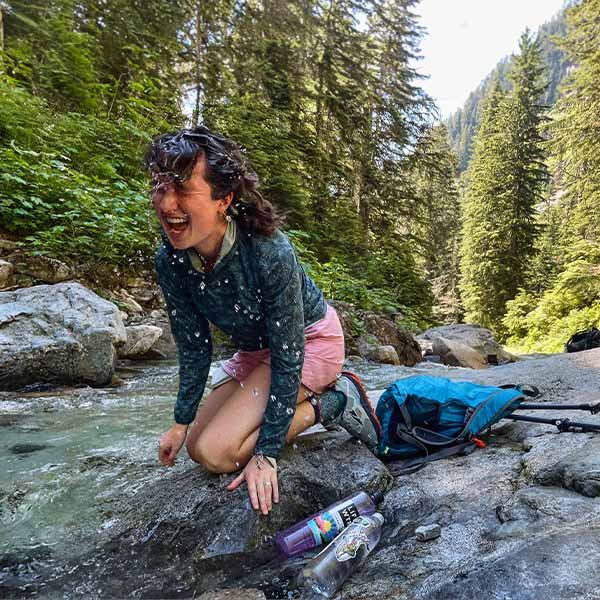 Woman laughing while dipping her hair in a river.
