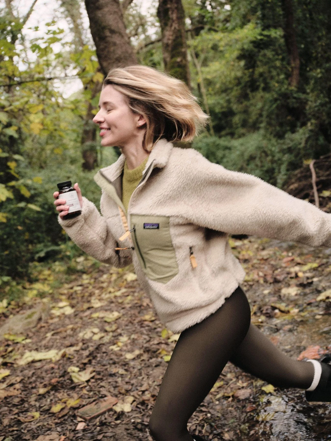Woman running through a forest in a fleece jacket