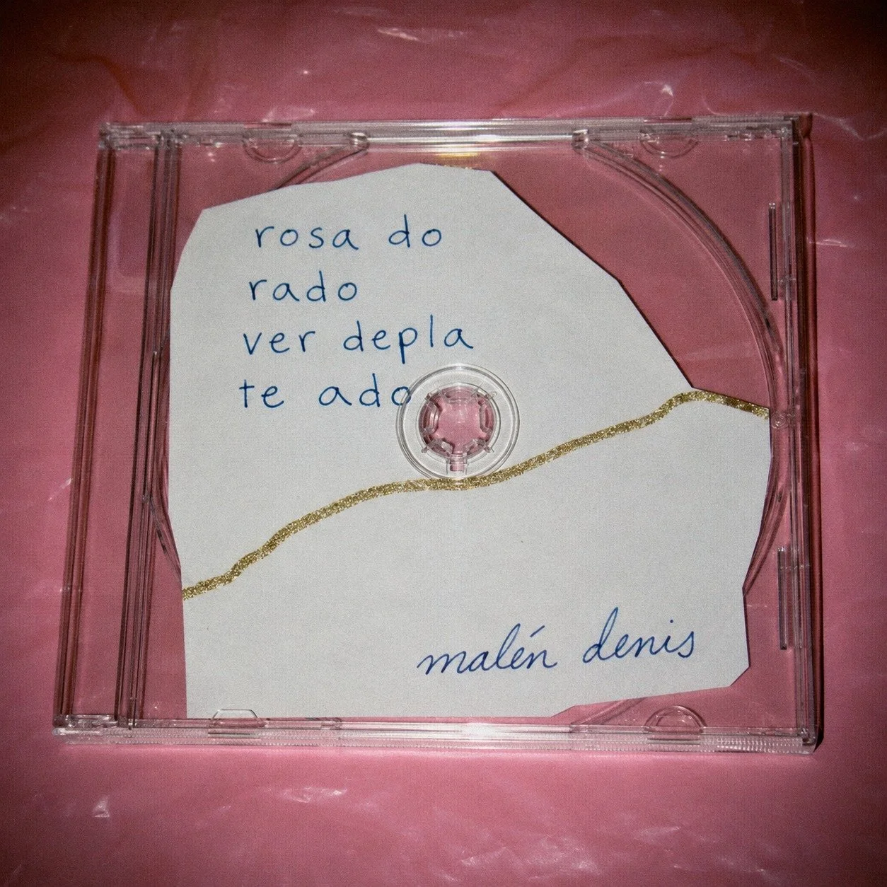 Album cover: clear CD case on pink plastic with torn paper lettering