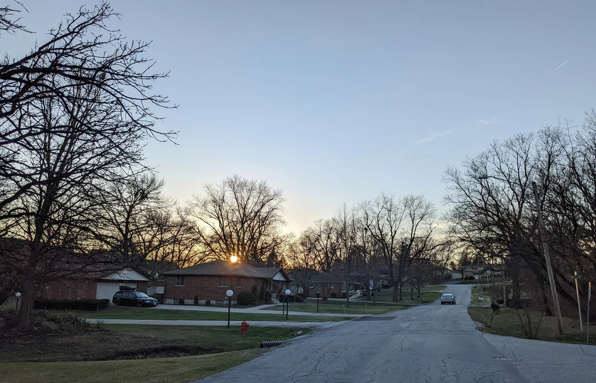 A quiet Hickory Hills street of brick ranch homes at sunset