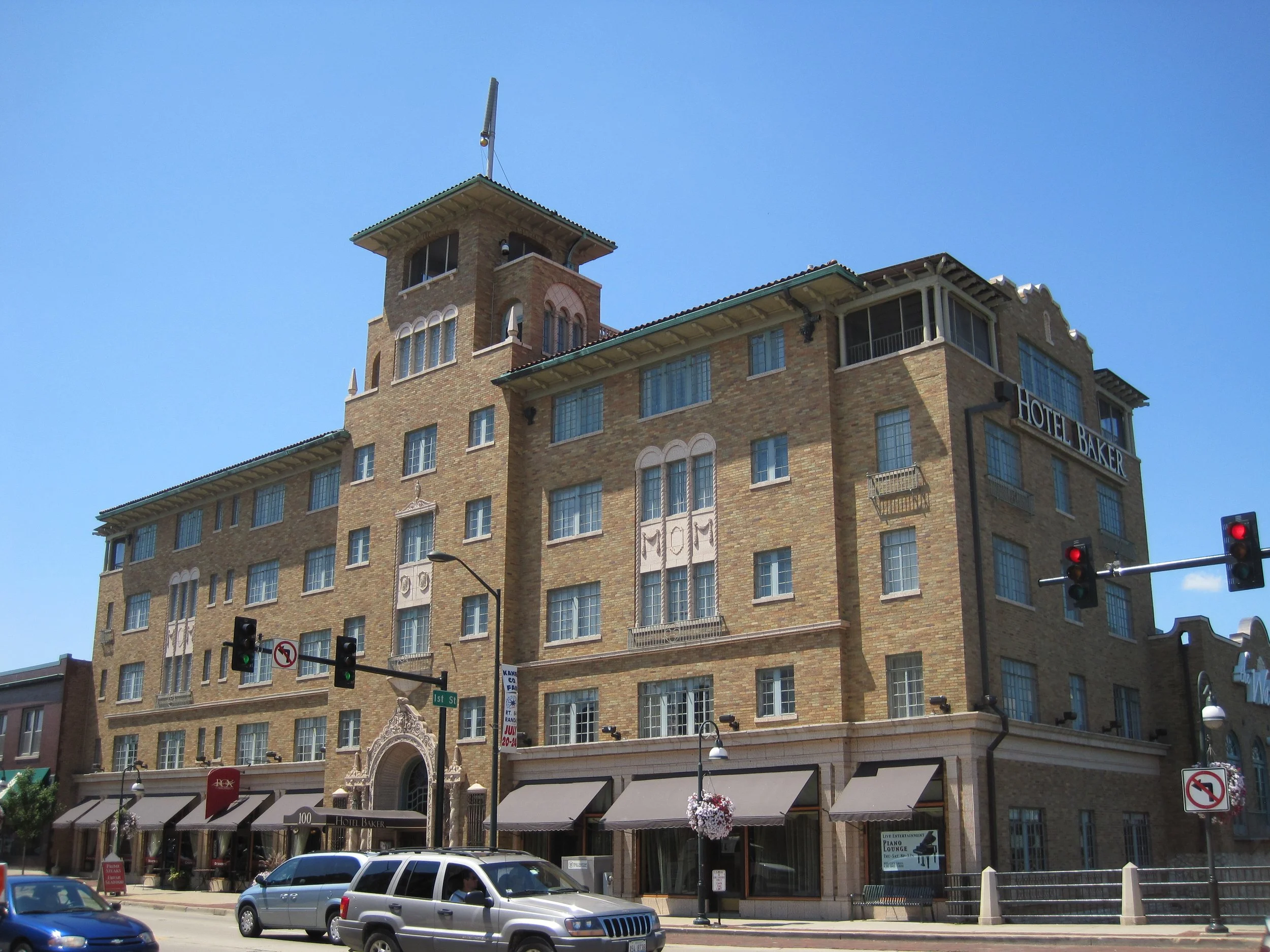 Hotel Baker in downtown St. Charles, a brick building with its name sign and a tower, under a blue sky