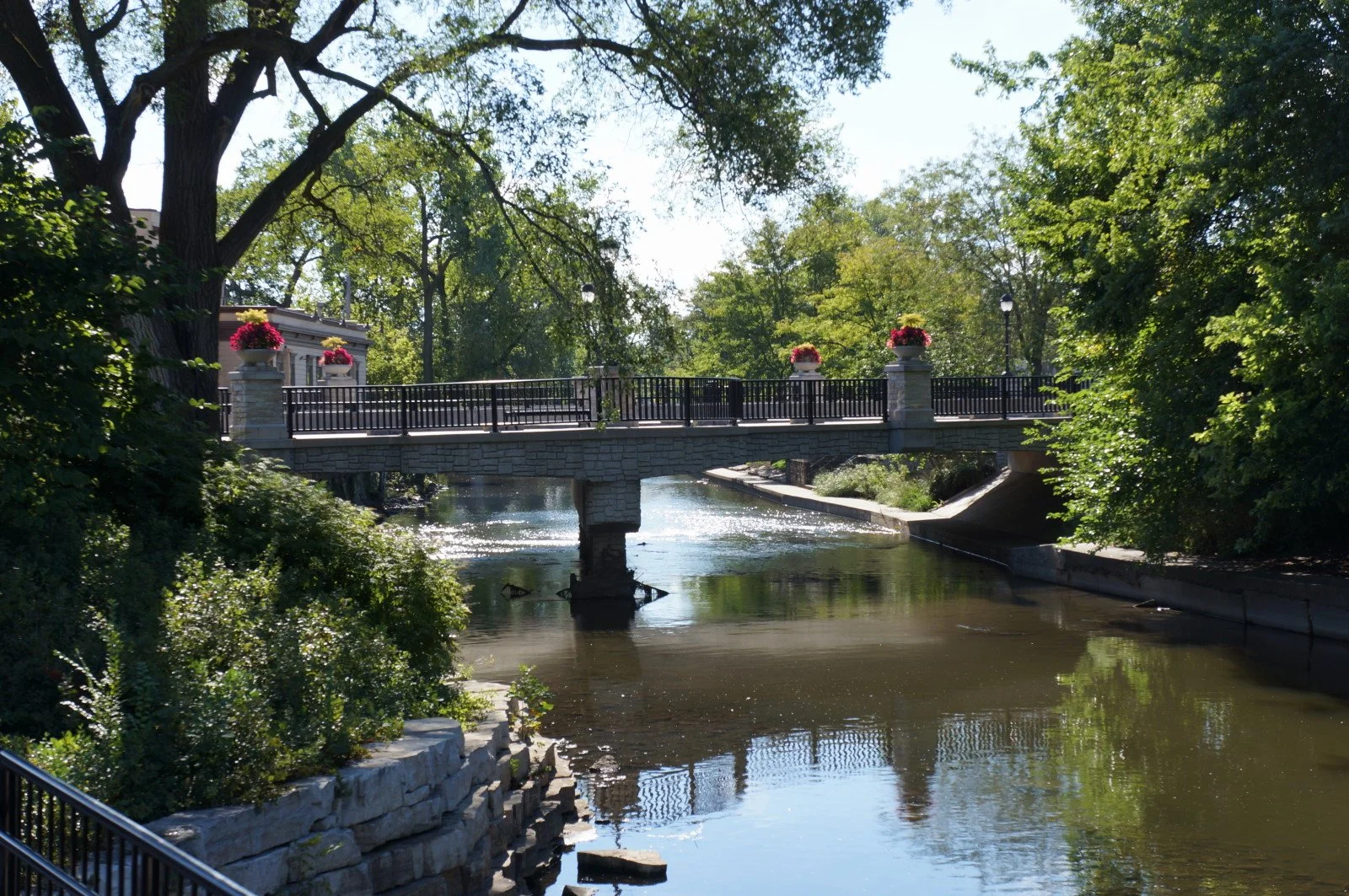 A footbridge with flower planters crossing the DuPage River on the Naperville Riverwalk