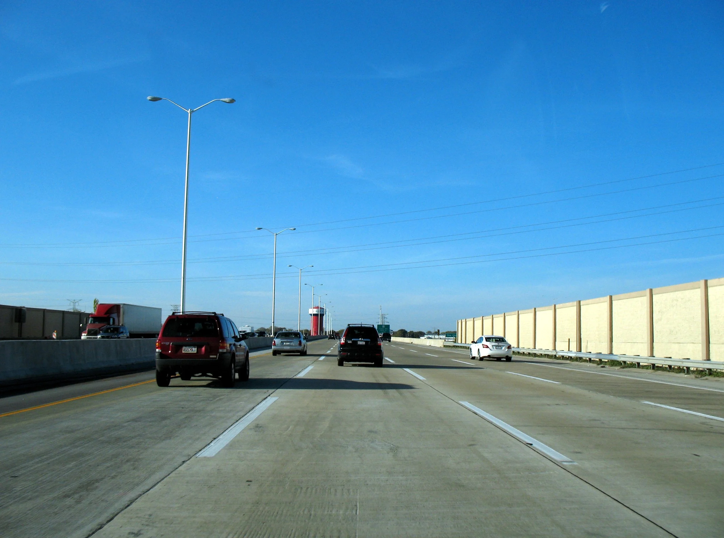 Northbound lanes of the Tri-State Tollway in Alsip under a blue sky, with a red water tower ahead