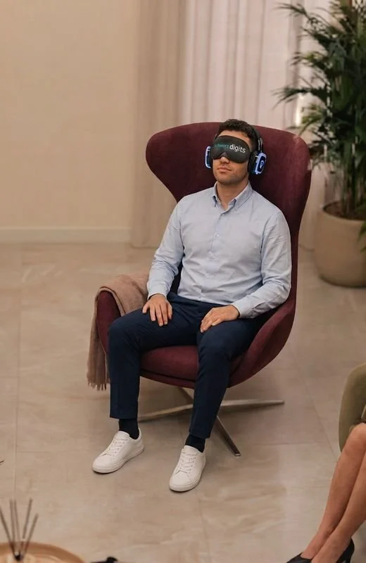 Man relaxing in an armchair with headphones and an eye mask during a breathing session
