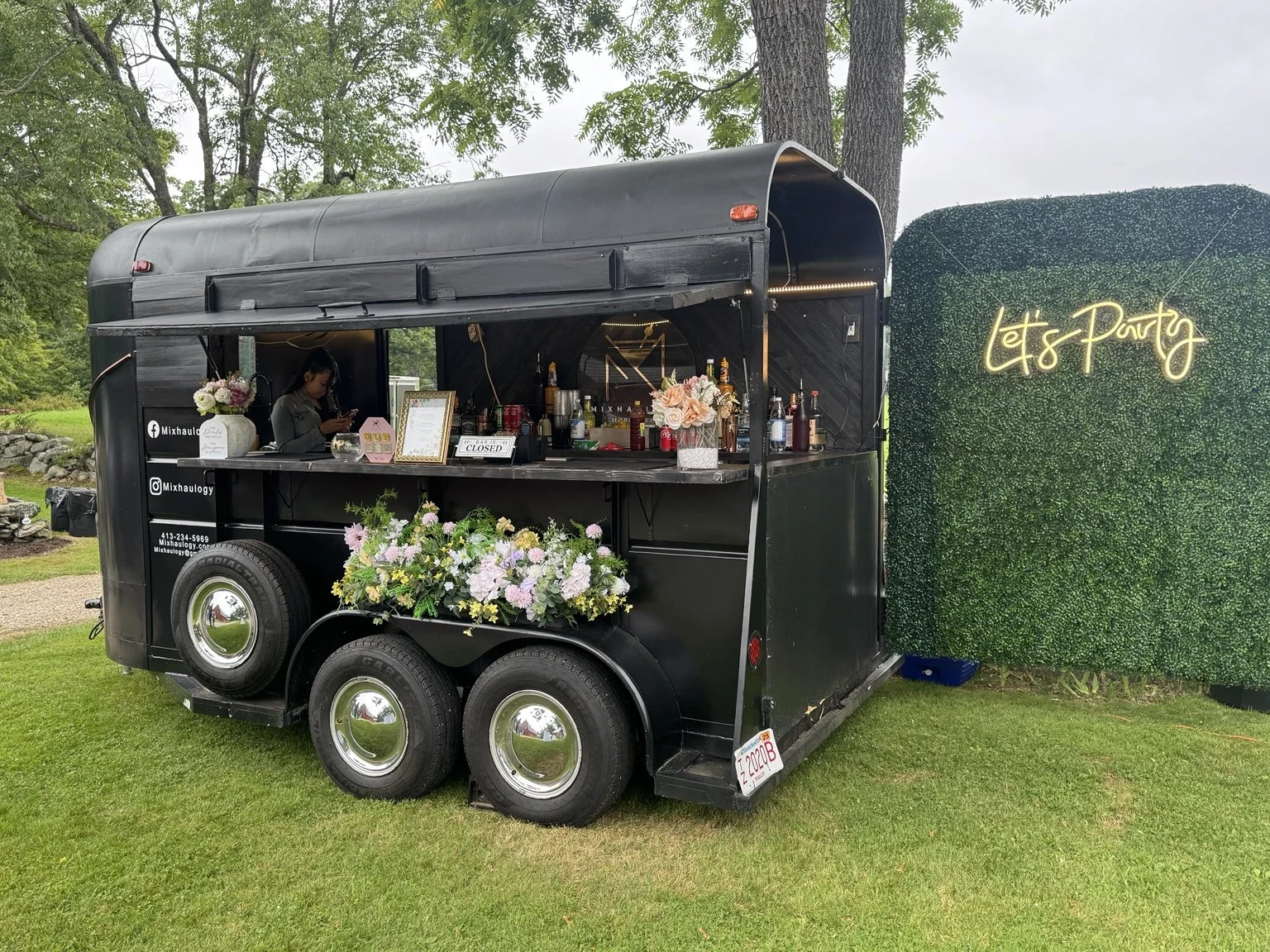 Mixhaulogy vintage trailer with floral arrangements and a greenery backdrop outdoors