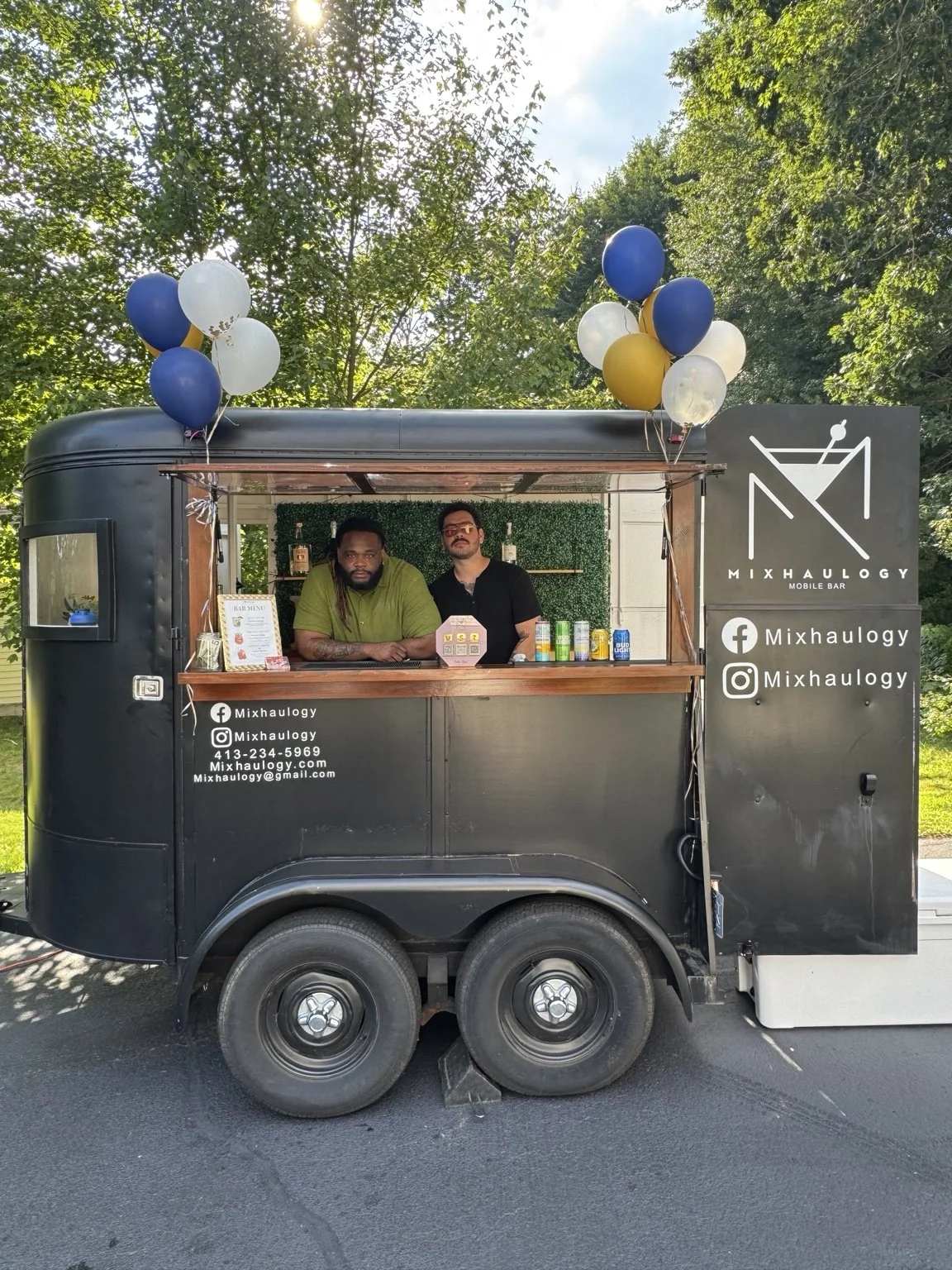 Two Mixhaulogy team members in the small trailer decorated with balloons