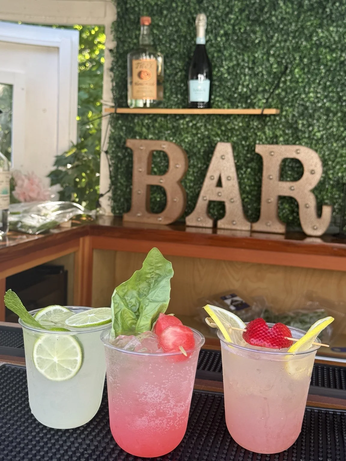 Three colorful signature cocktails with citrus and berry garnishes at the Mixhaulogy bar