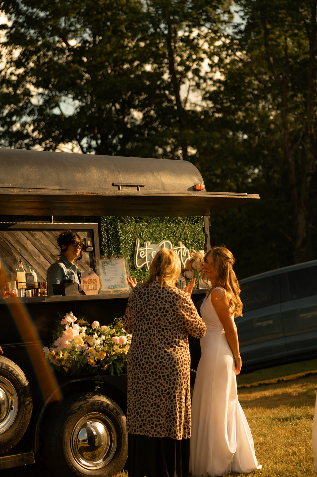 A bride and guest enjoying the Mixhaulogy trailer at golden hour