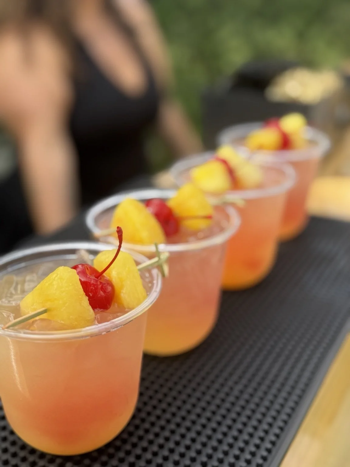 Mixhaulogy cocktails lined up with pineapple and cherry garnishes