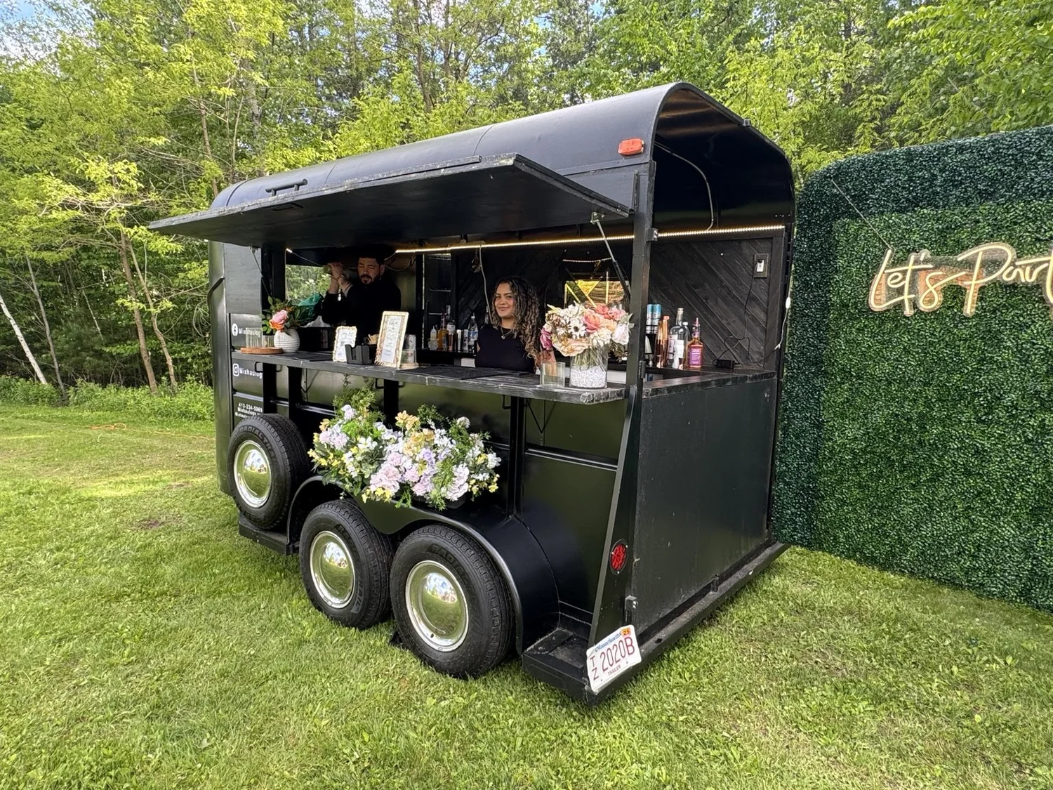 Mixhaulogy vintage trailer with bartenders, flowers, and a Let’s Party backdrop